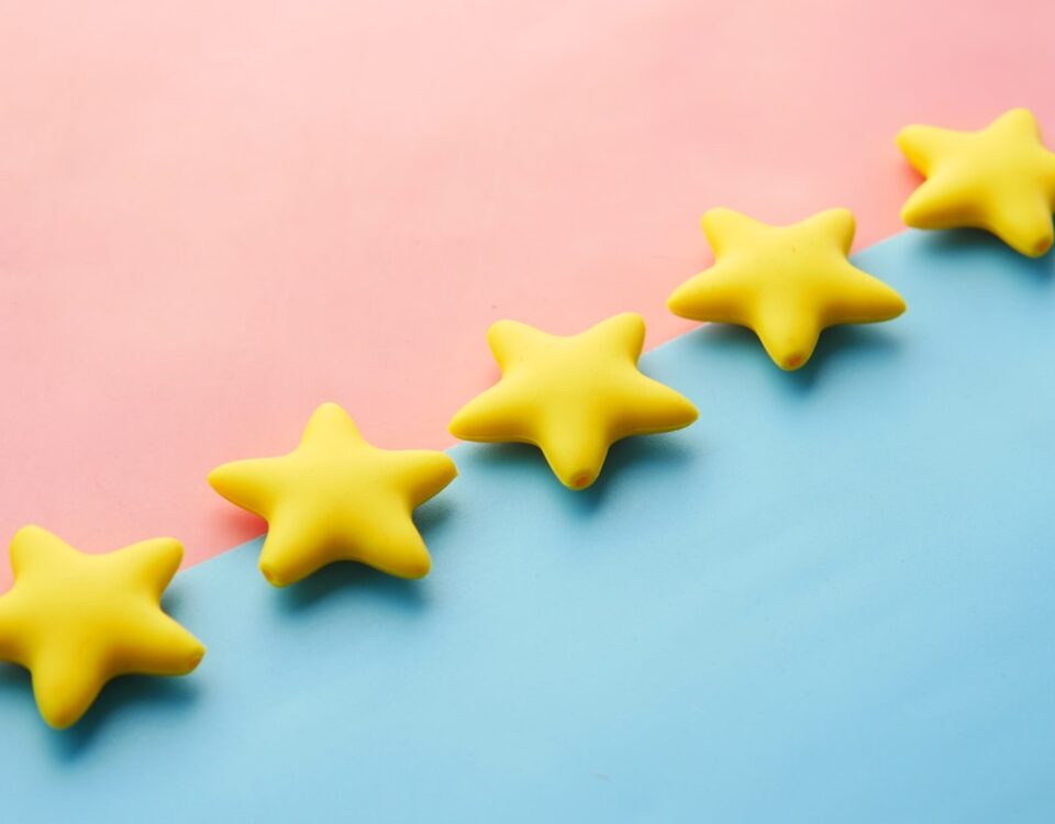 5 apps para monitorar avaliações online e manter sua reputação a row of yellow stars sitting on top of a blue and pink surface
