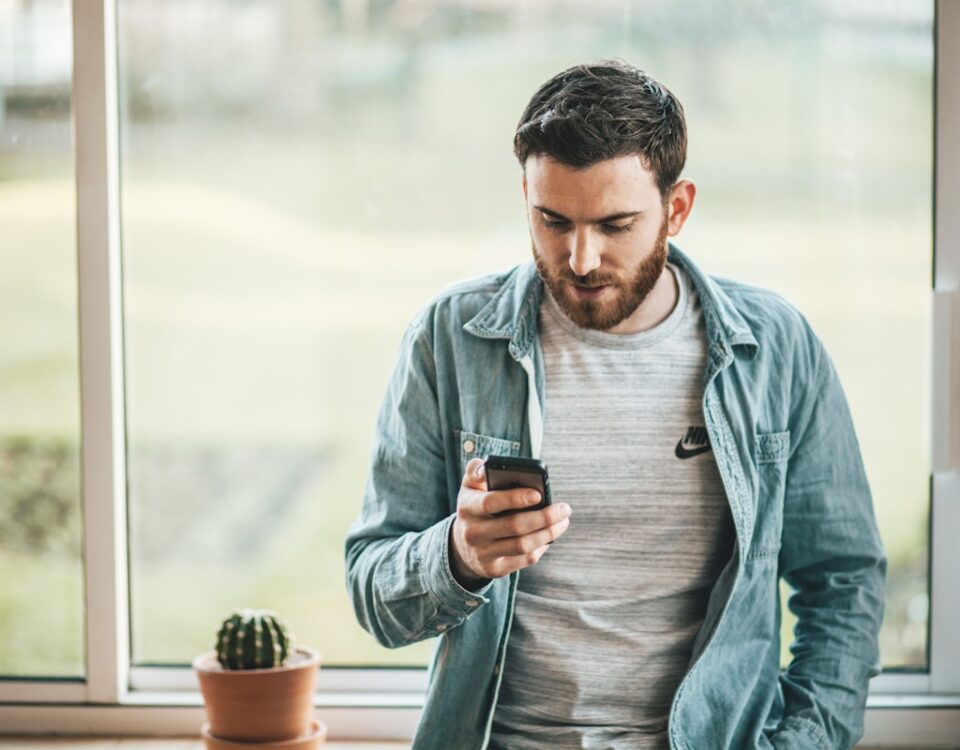 5 softwares e plataformas que surgiram de invenções inesperadas man holding a smartphone near the window