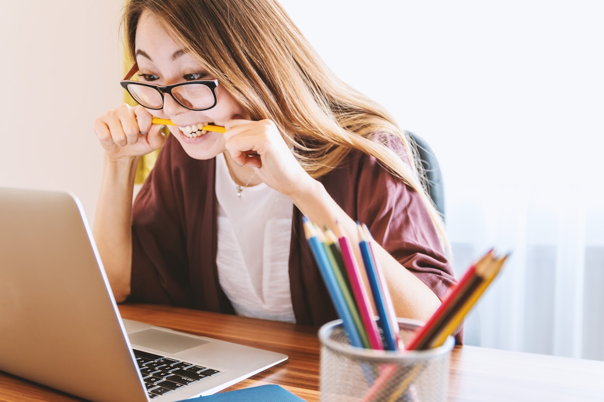 5 apps para gerenciar seus diplomas e certificados woman biting pencil while sitting on chair in front of computer during daytime