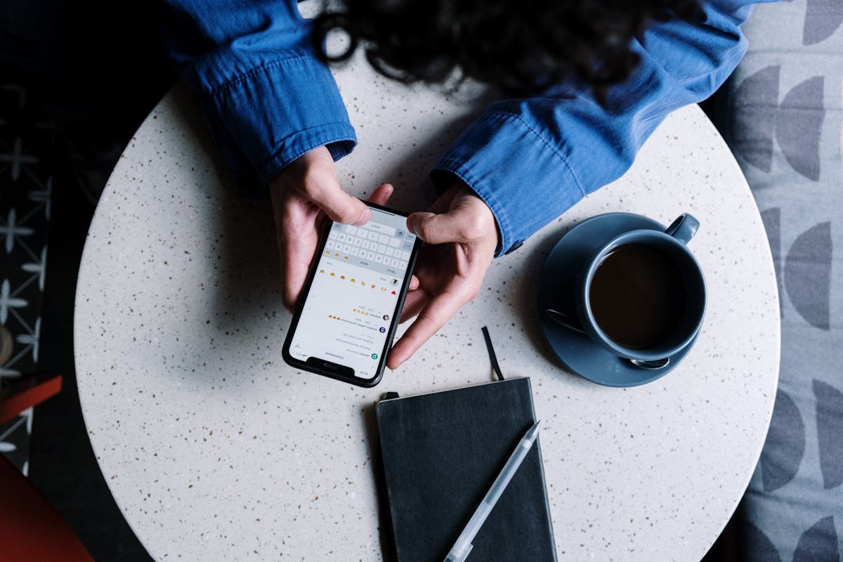 Entenda como funcionam os softwares para criar chatbots no WhatsApp Person in Blue Denim Jacket Holding Black Smartphone