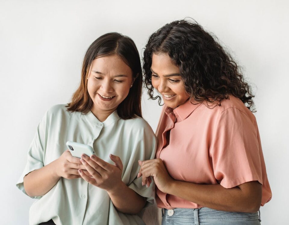 5 Apps que Revelam Curiosidades Sobre o Mundo ao Seu Redor Women Smiling while Looking at the Smartphone