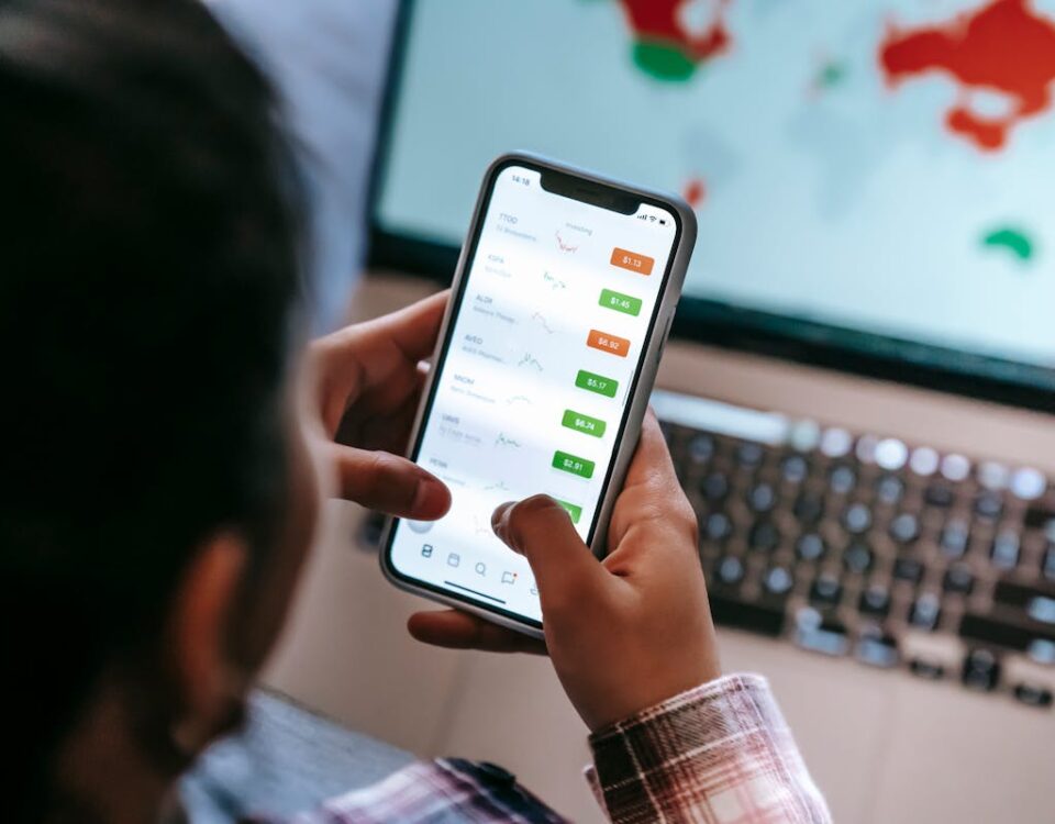 5 Apps para monitorar gastos e melhorar suas finanças Crop broker using trading app on smartphone against laptop