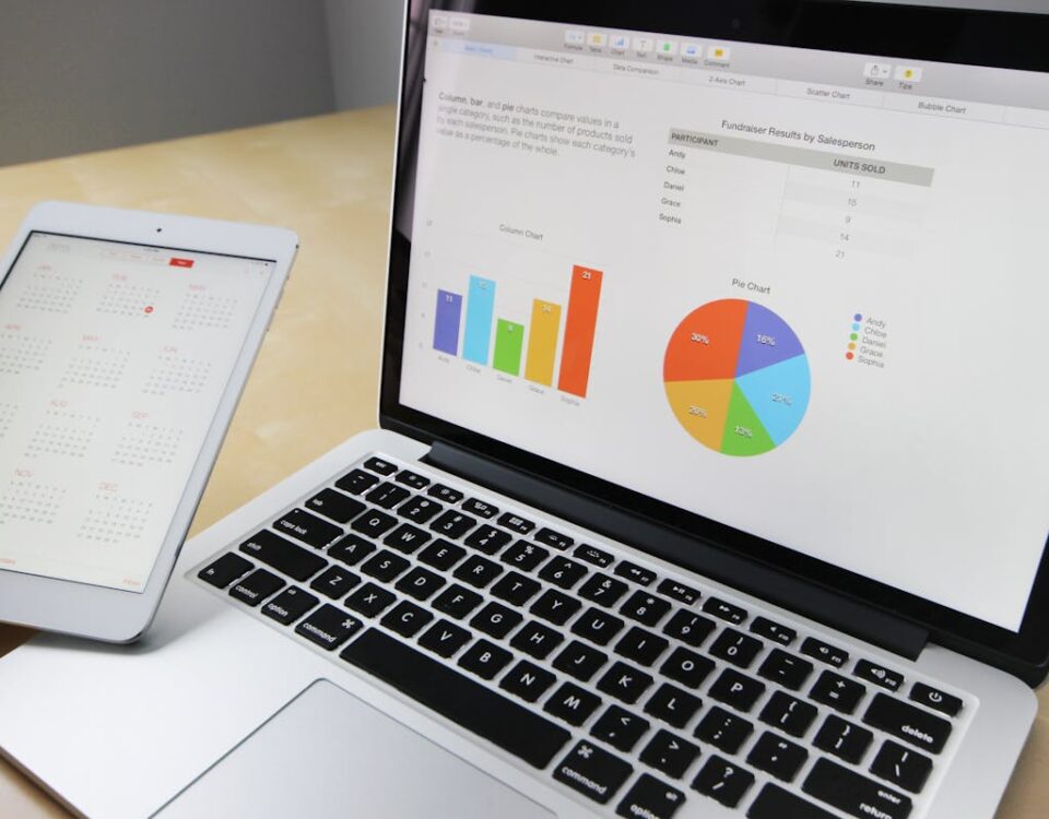 Como sistemas otimizam a gestão de estoque e vendas Laptop displaying charts and graphs with tablet calendar for data analysis and planning.