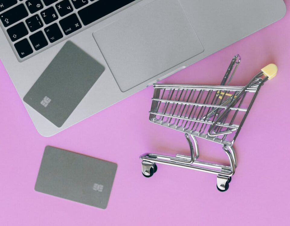 Estratégias para Recuperar Carrinhos Abandonados e Leads Inativos A minimalist flat lay of a credit card, laptop, and miniature shopping cart.