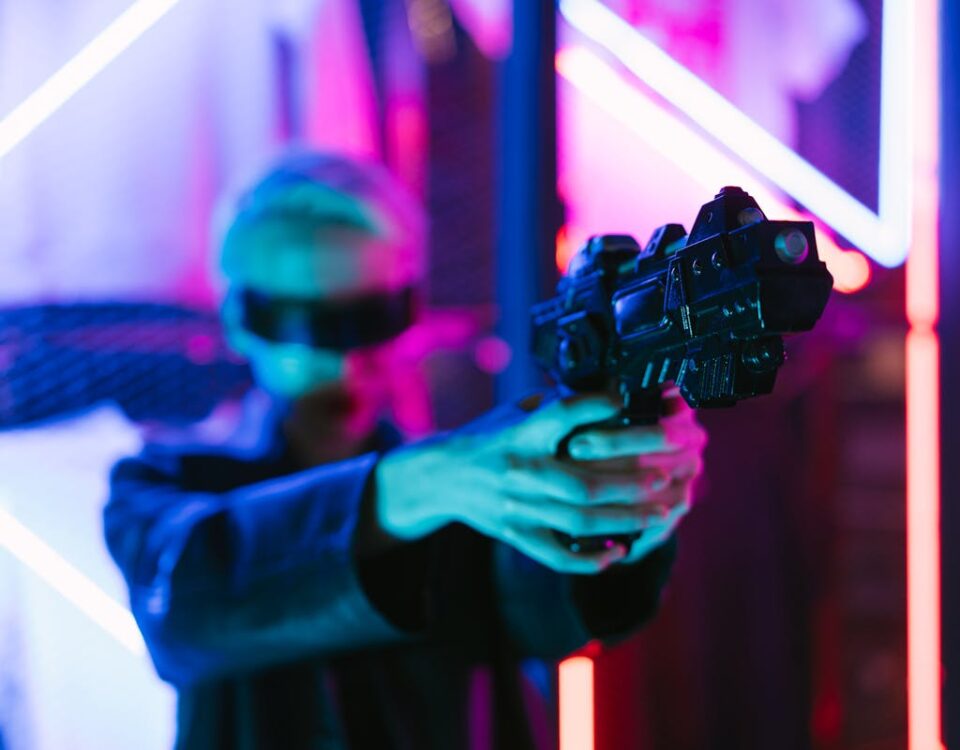 5 simuladores de tiro para treinamento virtual A woman in cyberpunk fashion holding a futuristic weapon against a neon backdrop.