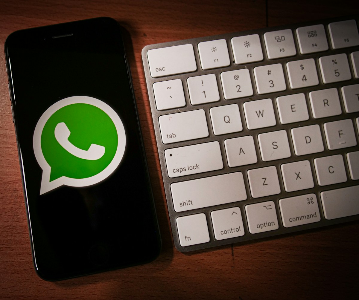5 softwares para criar bots de atendimento no Whatsapp a phone with a whatsapp sticker next to a keyboard
