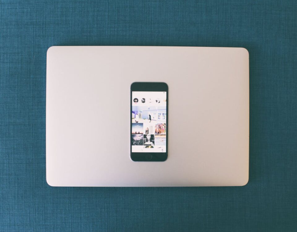 5 painéis SMM que fazem a diferença no dia a dia Flat lay of a smartphone on a laptop with social media photos on screen.