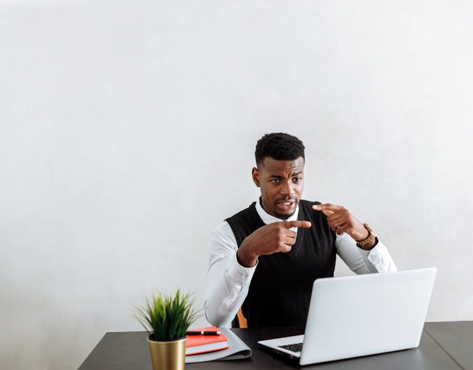 5 tipos de softwares essenciais para advogados criminais Professional businessman explaining during video call using laptop in modern office setting.