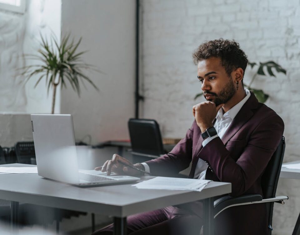 5 softwares essenciais para escritórios de advogados criminalistas Businessman in corporate attire focused on laptop work in a modern office environment.