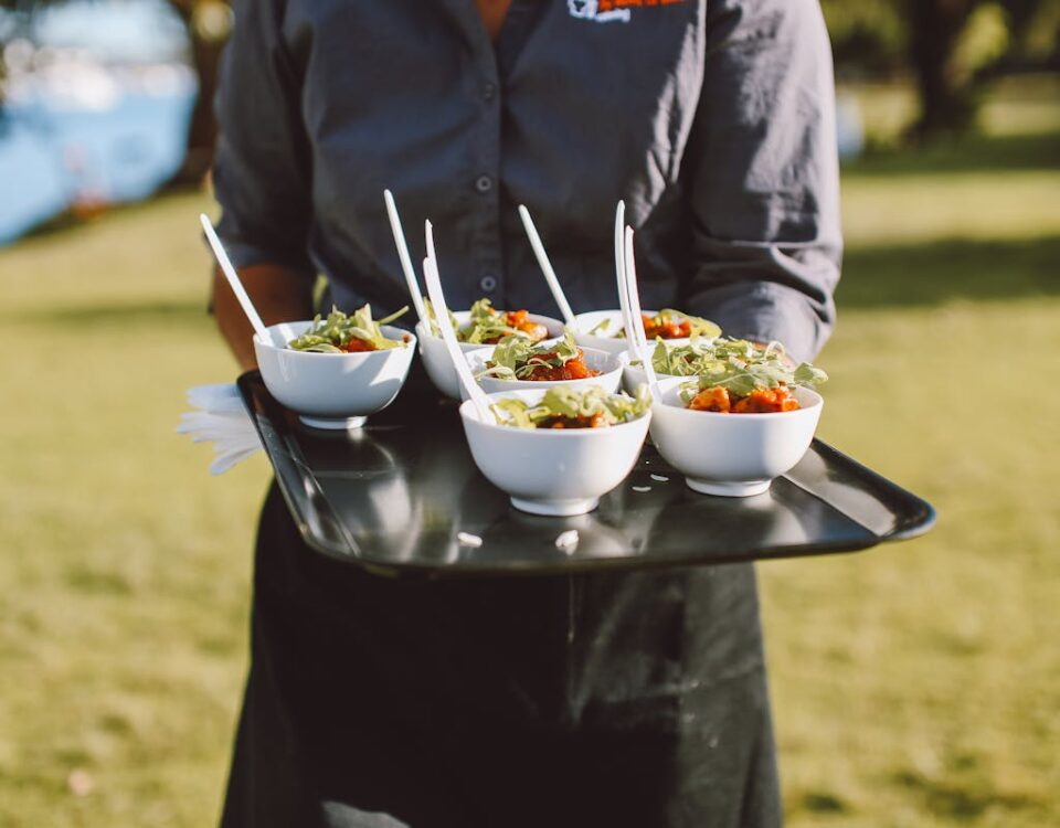 5 softwares para organizar buffets com eficiência Catering service offering fresh salad bowls outdoors, featuring vibrant greens and cherry tomatoes.