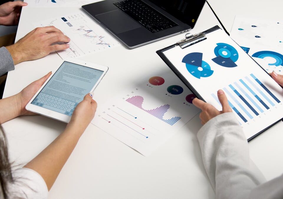 5 softwares de automação comercial que você precisa conhecer Team analyzing financial charts and digital reports during a business meeting.