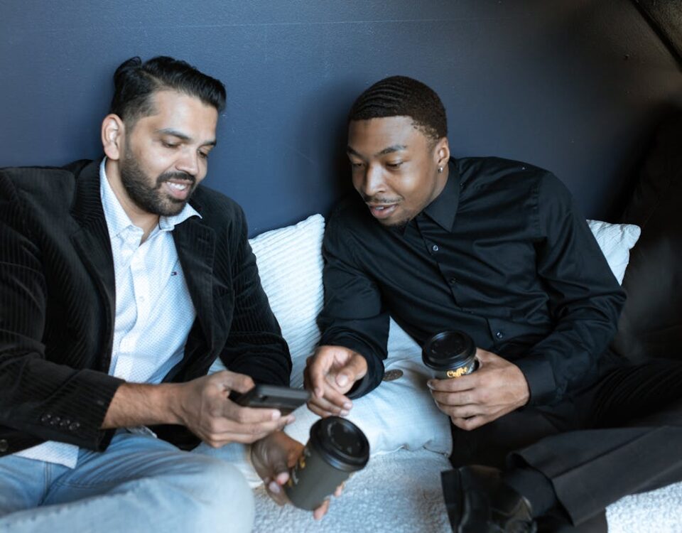 5 apps para comparar seguros e economizar Two men enjoying coffee during a relaxed business meeting indoors.