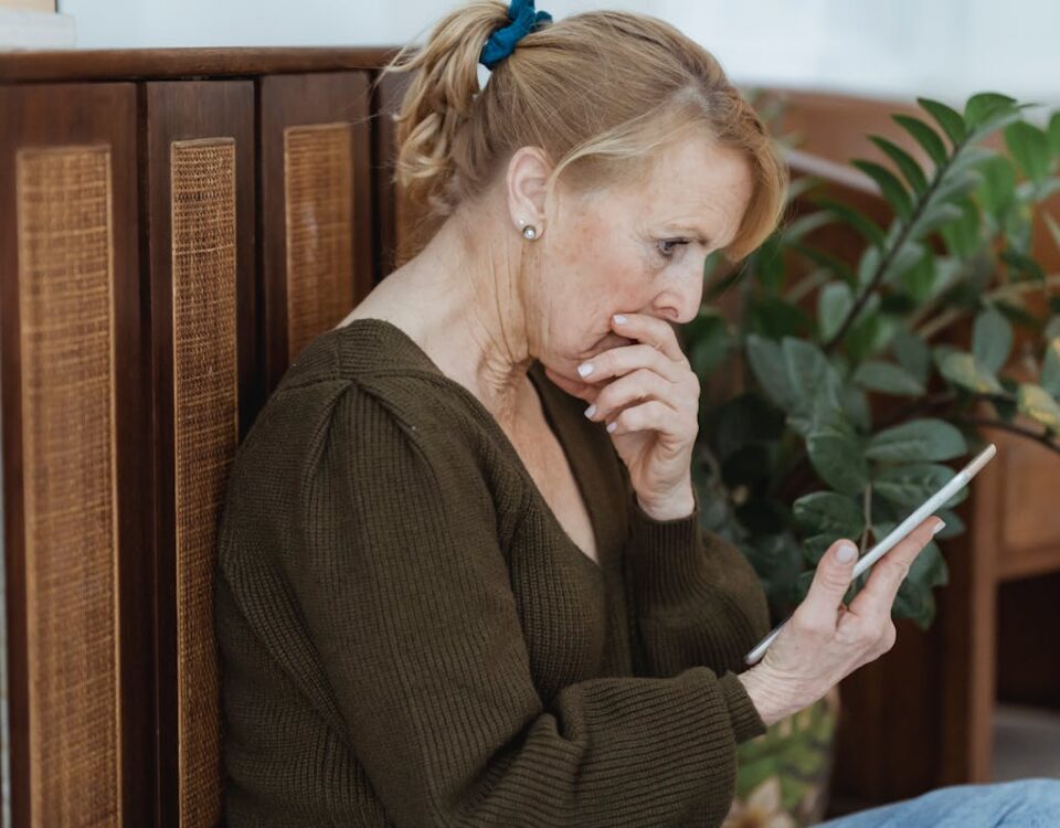 5 aplicativos para se manter atualizado com notícias Senior woman deeply focused on her smartphone, indoors with plants and cozy decor.