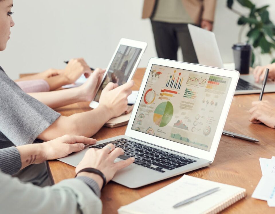 5 softwares para criar anúncios profissionais com facilidade Coworkers analyzing data charts on laptops during a team meeting.