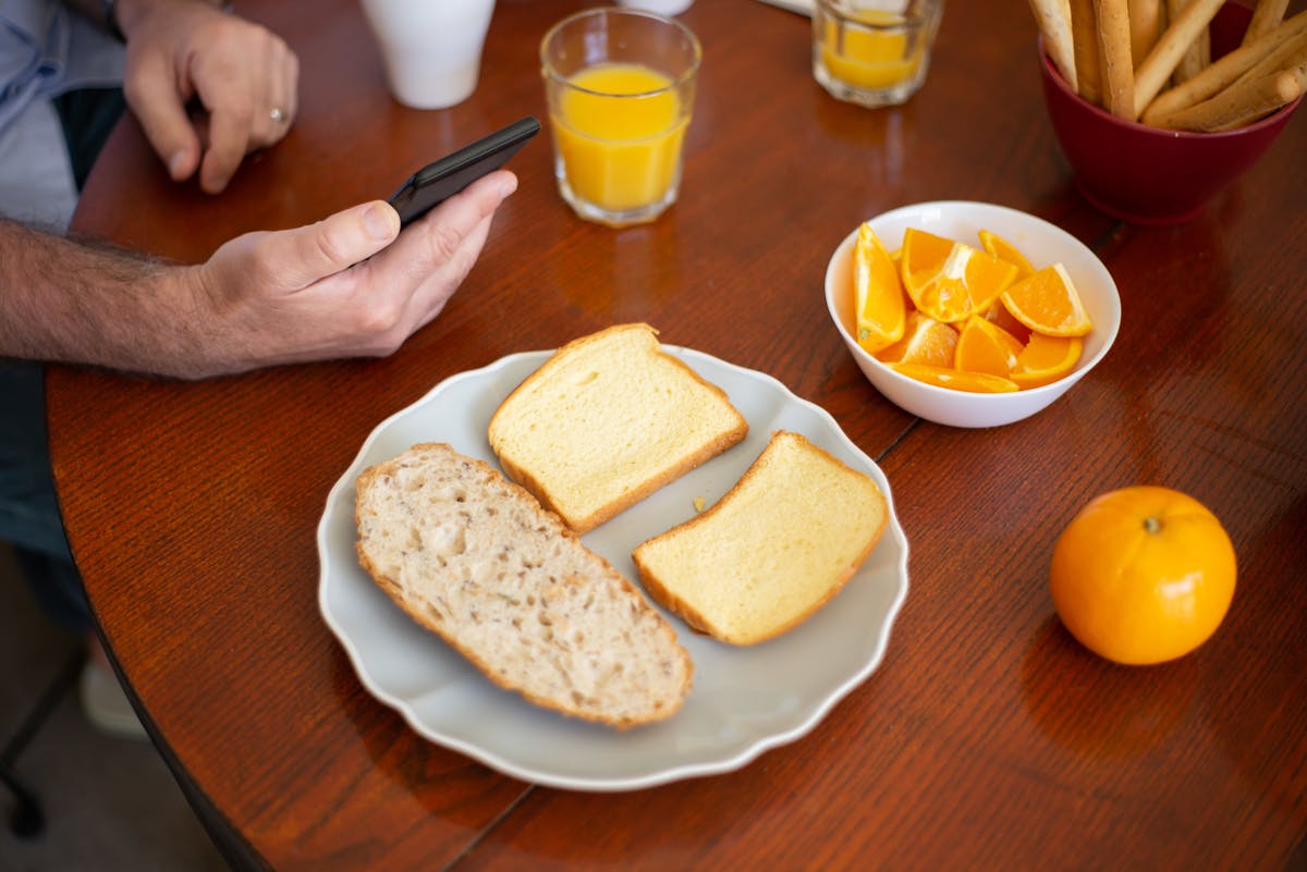 5 apps que ajudam a planejar suas refeições Plate with assorted bread and a bowl of orange slices on a breakfast table in Portugal.