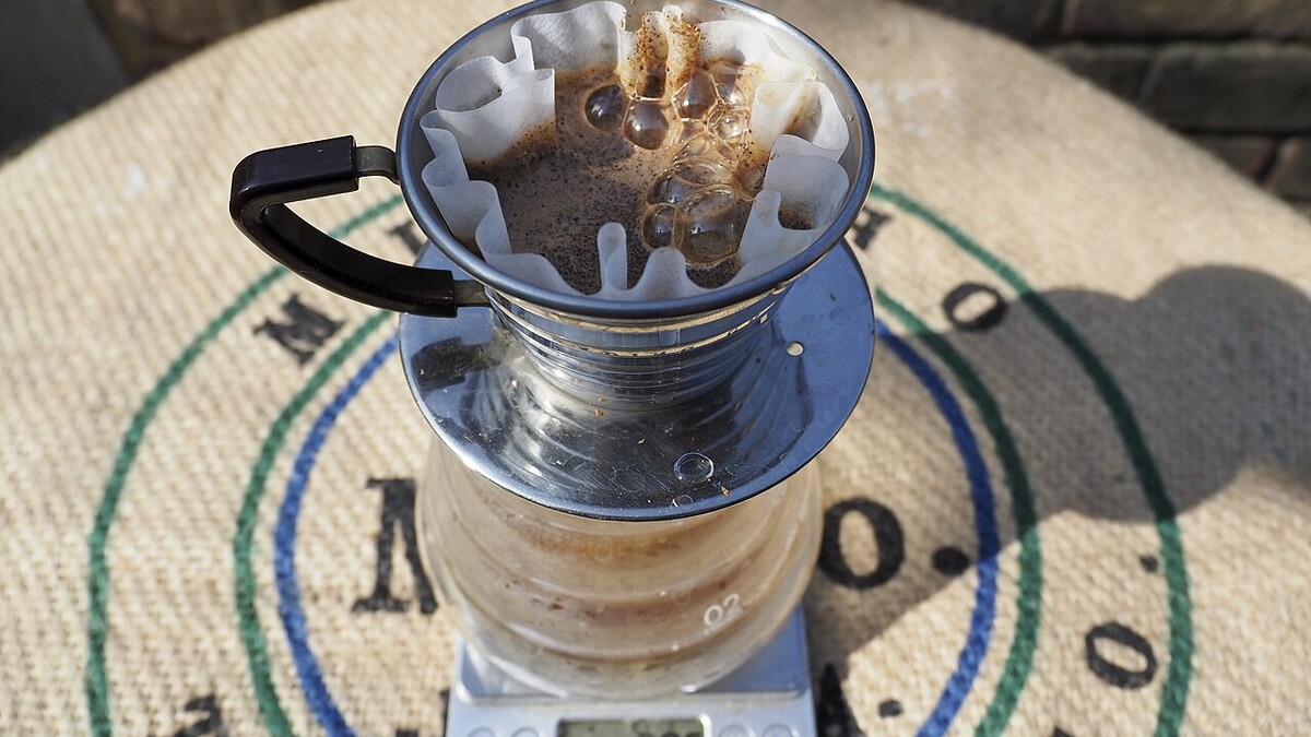 Apps ajudam a repetir a receita perfeita de café em casa? Café sendo coado em coador de fundo plano sobre jarra de vidro