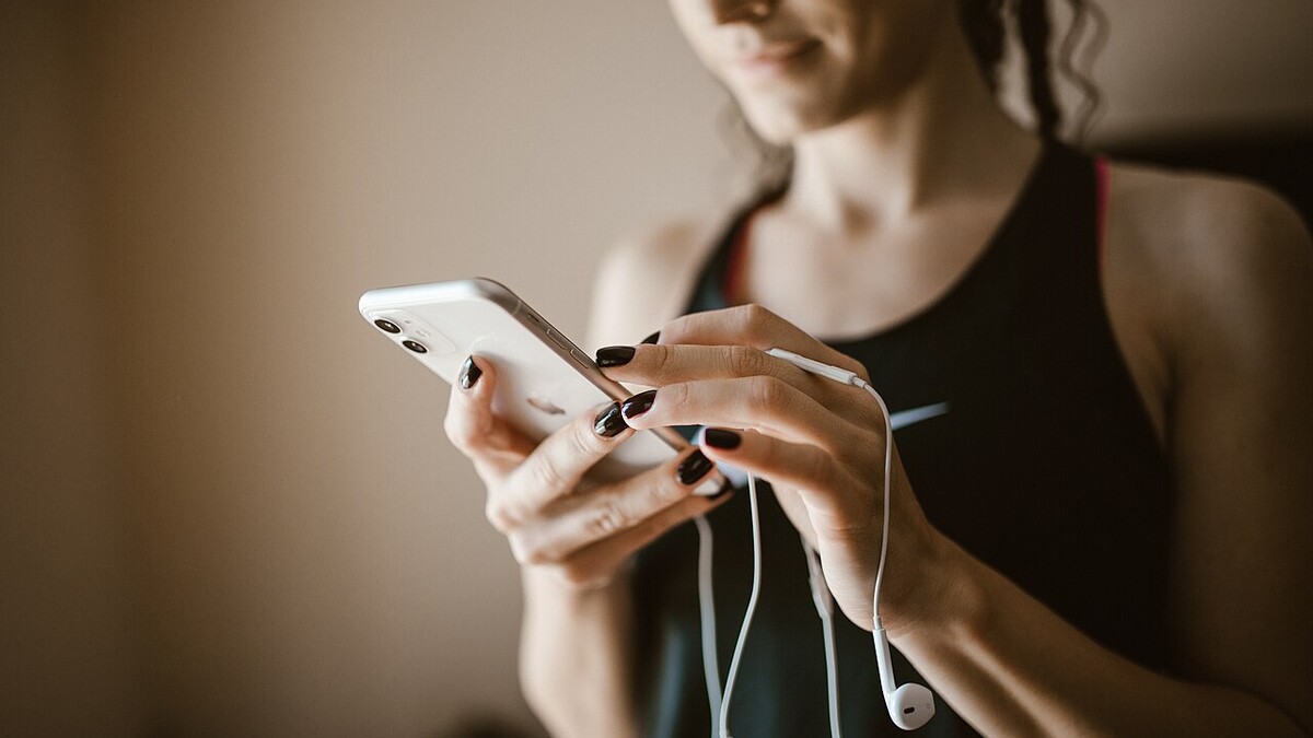 Mulher com fones de ouvido com fio mexendo no celular
