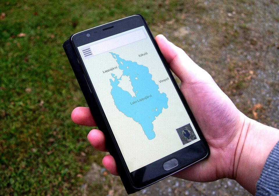 Mão segurando celular com aplicativo aberto na tela, ao ar livre