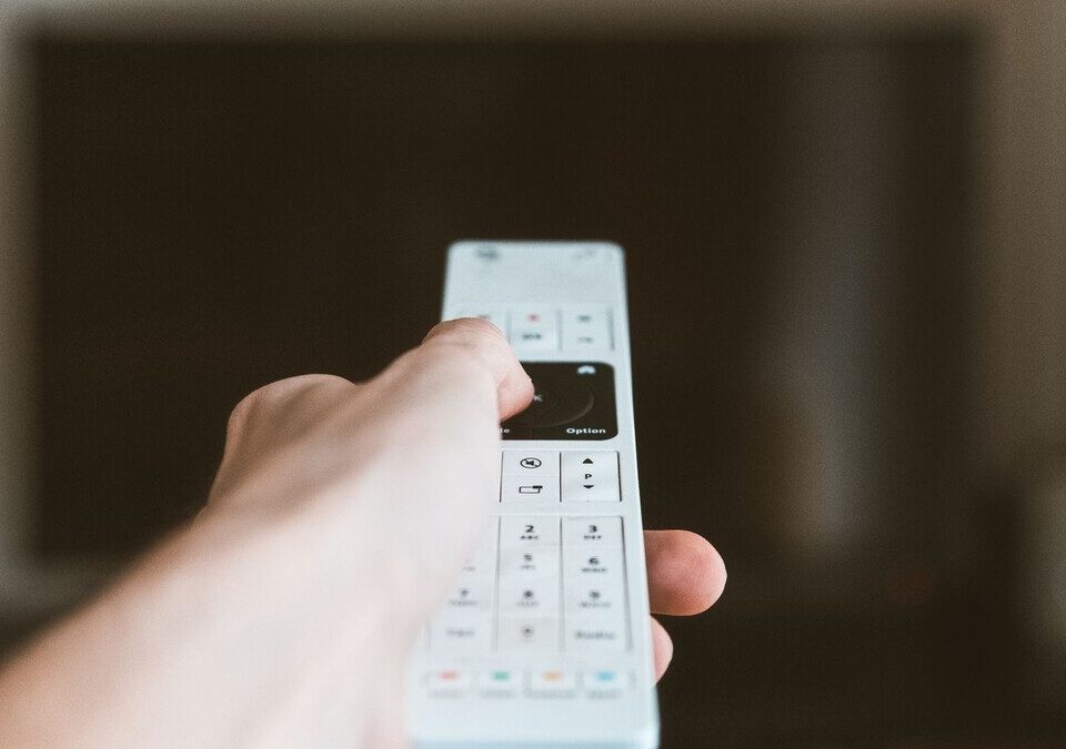 Disney+ Premium perde 4K e HDR no Brasil: o que o assinante pode fazer Mão segurando controle remoto diante de uma TV ligada