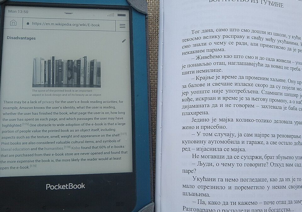 Leitor de livros digitais ao lado de um livro impresso aberto