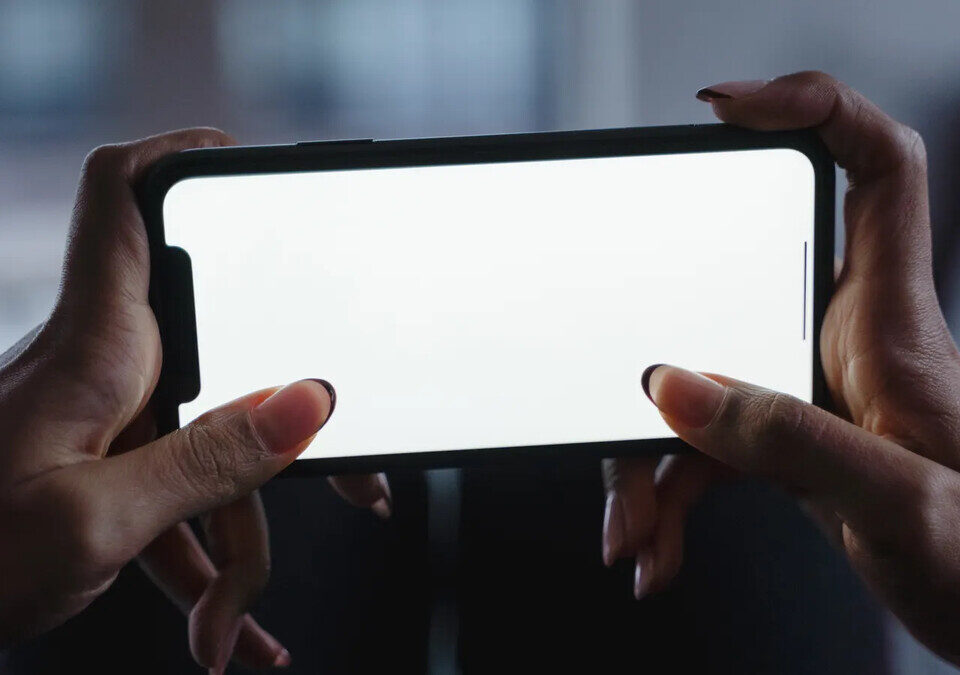 Mãos segurando um celular com tela em branco