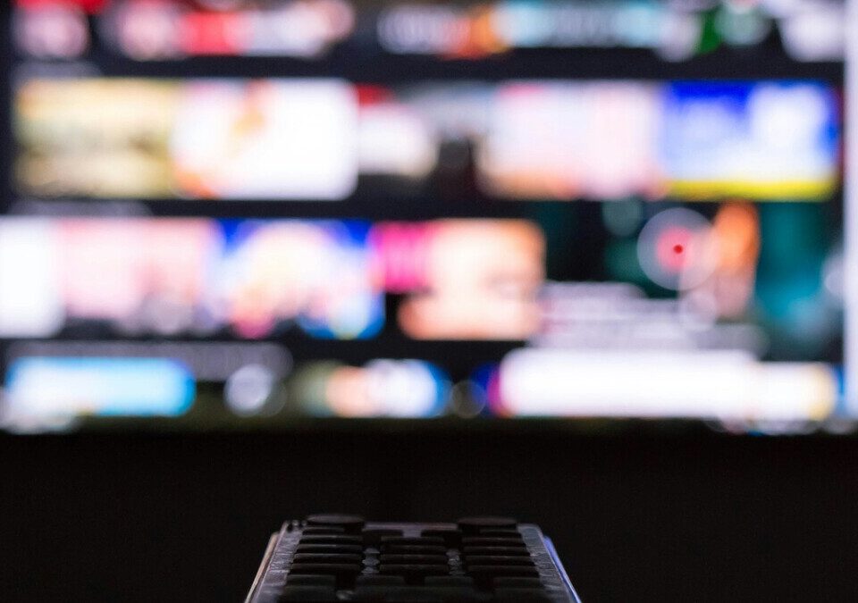 Netflix fica mais cara no Brasil: novos preços e quando a cobrança muda Controle remoto apontado para uma televisão com a tela desfocada