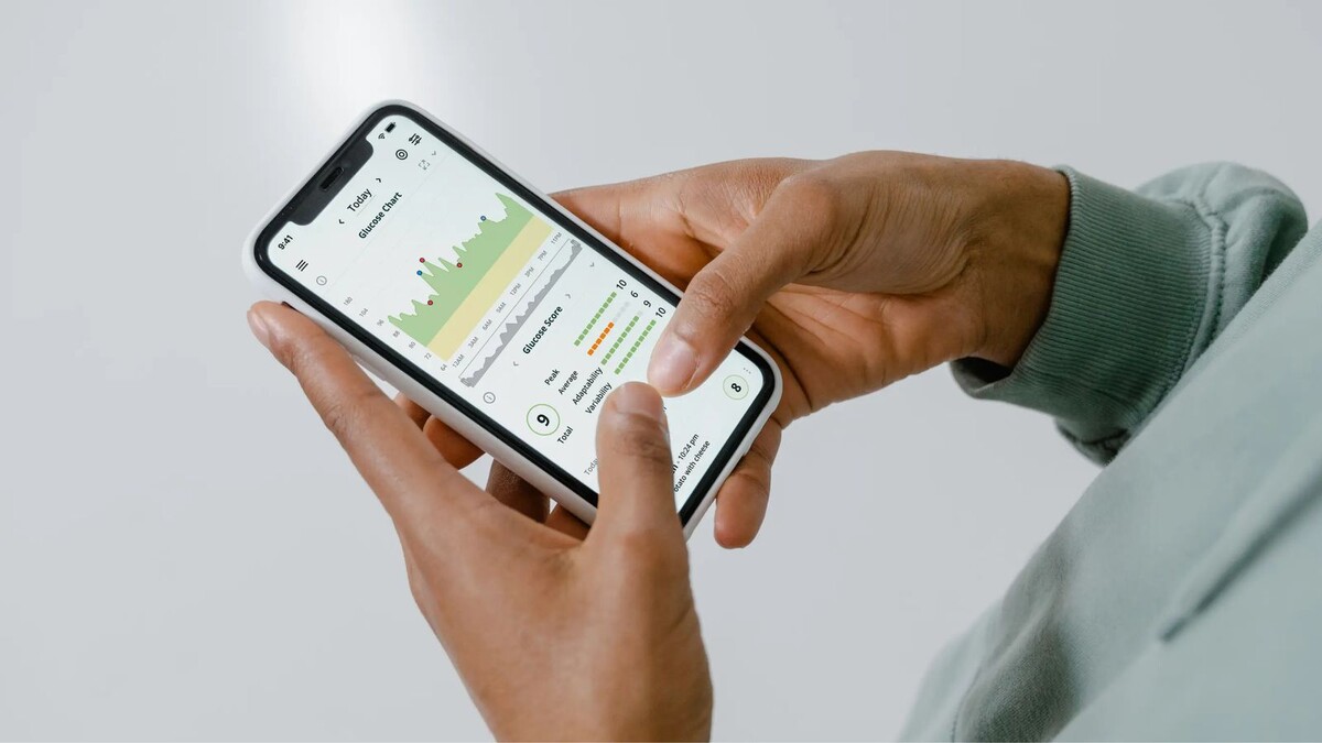 Mãos segurando um celular que exibe gráficos e dados de saúde