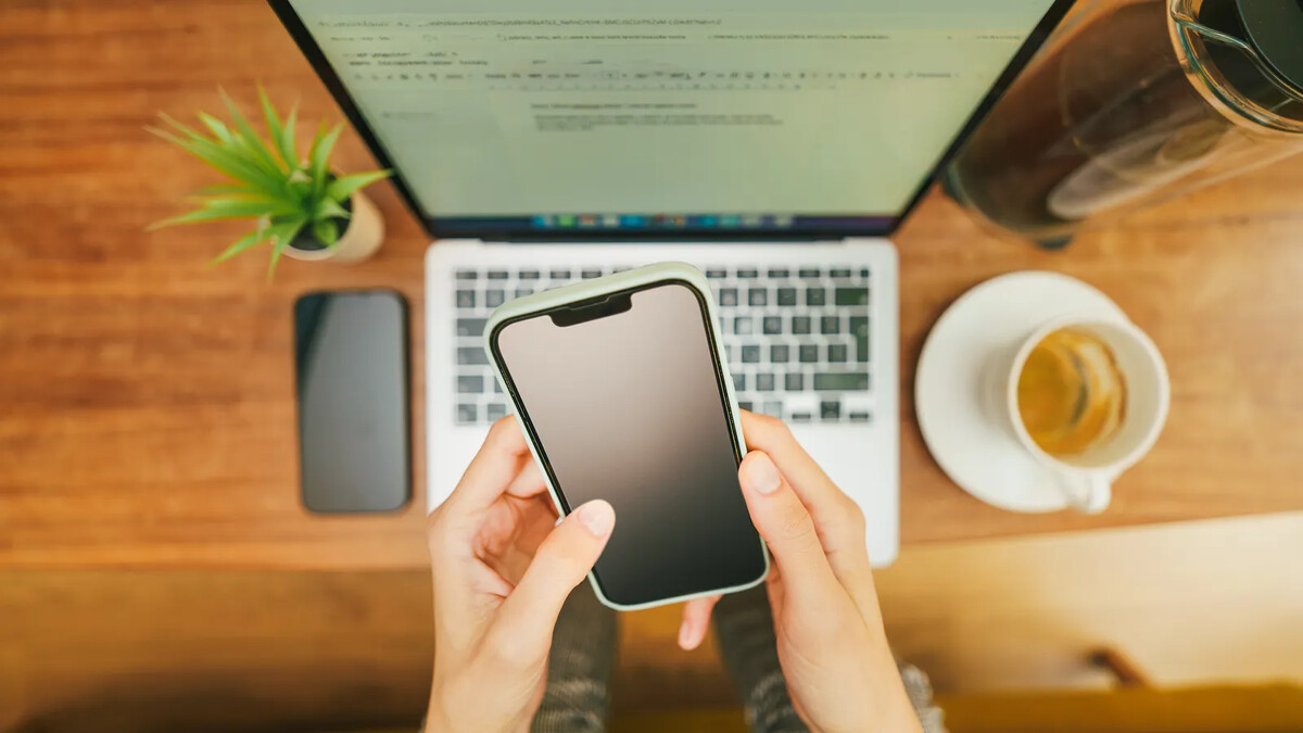 Celular apoiado sobre notebook em mesa de trabalho
