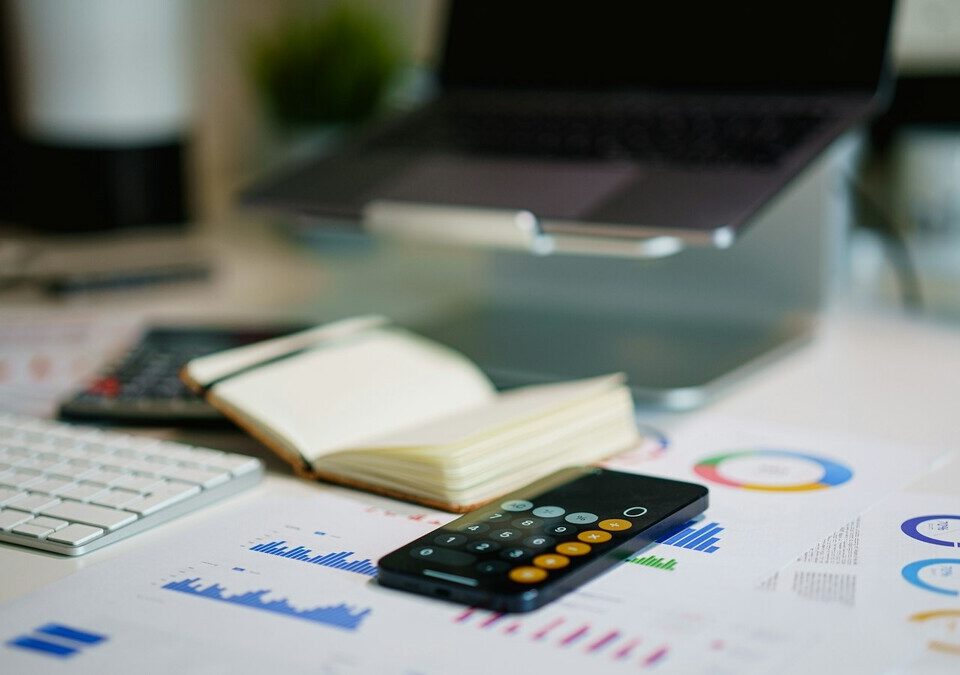 Mesa de escritório com smartphone e gráficos financeiros impressos