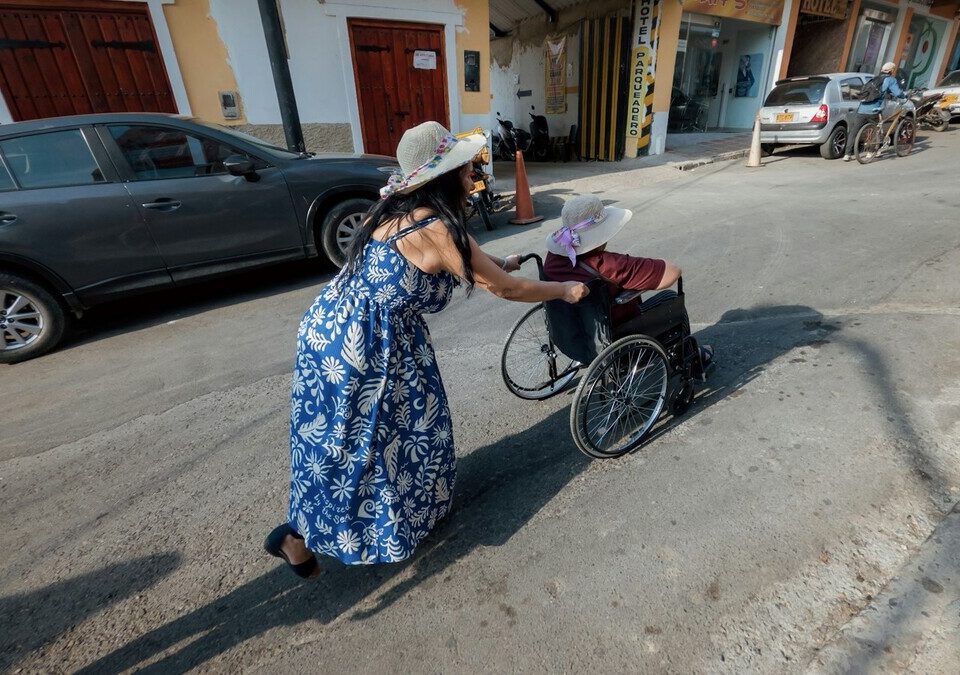 Uber lança Preferências de Partida: como ativar para idosos e PcD Mulher empurrando uma pessoa em cadeira de rodas numa rua